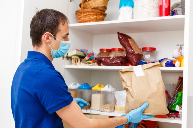 Uomo della pandemia di coronavirus in maschera protettiva e guanti con acquisti di cibo