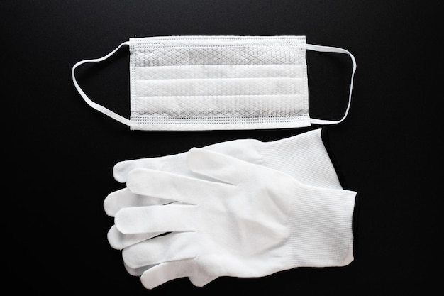 Coronavirus protection White antibacterial medical mask and protective gloves on a black background