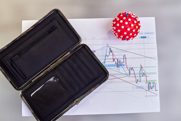 Modello rosso coronavirus con portafoglio vuoto e grafici.