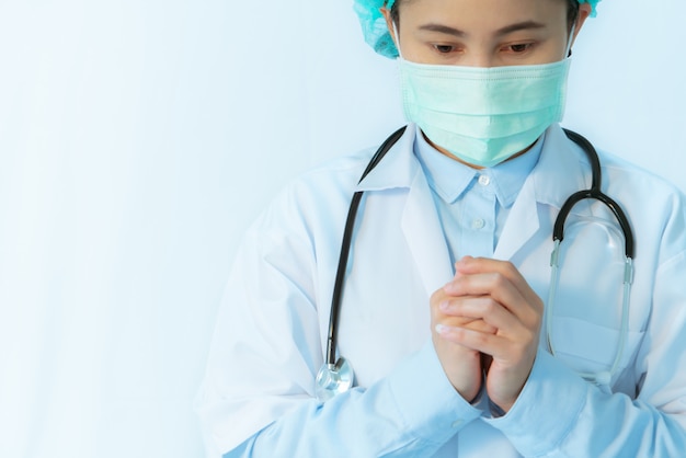Coronavirus stopt infectie. de jonge vrouwelijke arts die masker met stethoscoop draagt bidt voor met virus besmette persoon. Gezondheidszorg concept
