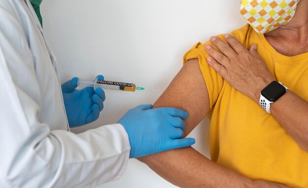 Коронавирус Шприц в руках врача, вводящего вакцину против коронавируса covid19 женщине
