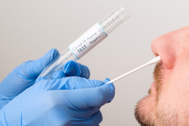 Медицинский работник или медсестра, проверяющие коронавирус, берут мазок из носа на образец коронавируса у пациента