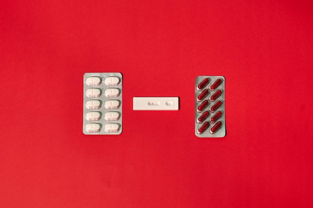 A coronavirus test and pills on a red background