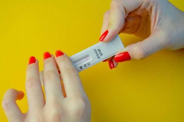 Тест на коронавирус на желтом ярком фоне медицинский анализ девушка с ярко-красным маникюром