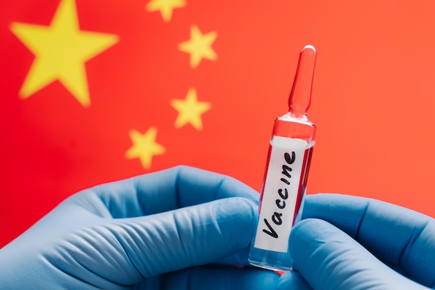 コロナウイルス治療のコンセプトです。中国の旗に対するCovid-19のワクチン。コロナウイルスワクチン研究。中国は世界的にウイルスをまき散らす中心です