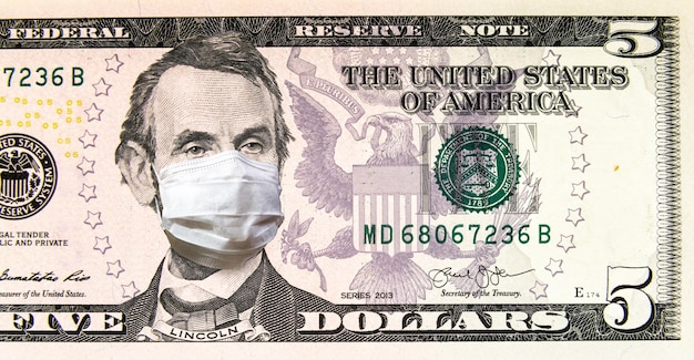 Coronavirus in USA 5 dollar money bill with face mask COVID19 affects global stock market World economy hit by corona virus pandemic fears