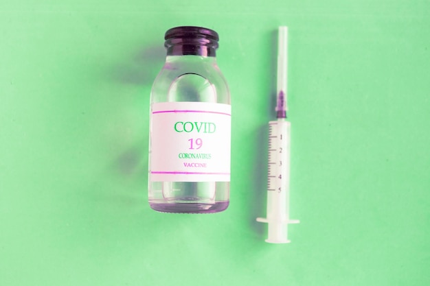 Coronavirus vaccin fles en spuit op blauwe pastel achtergrond Minimaal concept