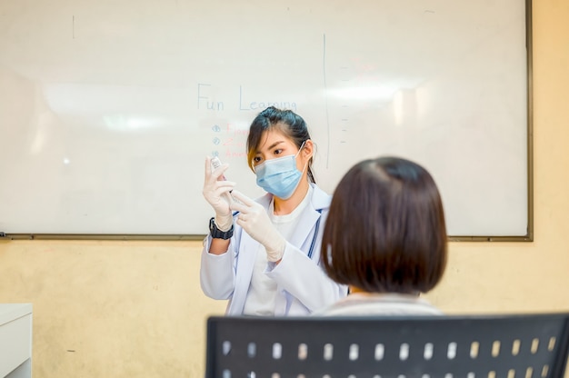 コロナウイルスワクチン接種。 COVID19ワクチン。児童の深刻な流行を防ぐために、学校で学童に予防接種を行う医師。インフルエンザの予防接種を受けている少年。ウイルス予防。