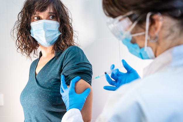 Coronavirus vaccine applied to a young woman by a doctor. Antibodies, immunize population.