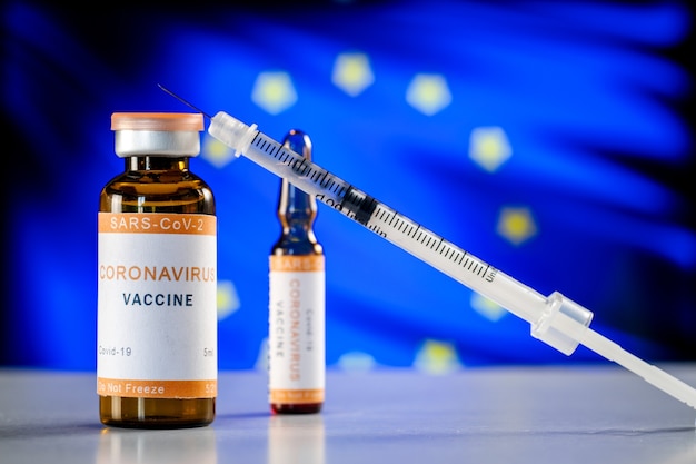 Foto vaccino contro il coronavirus covid19 e una siringa medica sullo sfondo della bandiera dell'unione europea