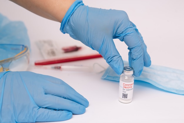 Coronavirus vaccine. Doctor with a vaccine. Hands holding a coronavirus vaccine ampoule, against Covid-19.