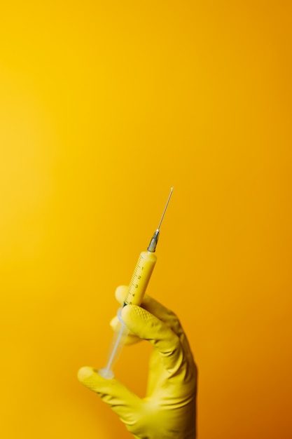 Coronavirus vaccine in yellow syringe, scientist in gloves holds syringe, curing for covid-19 curing. 