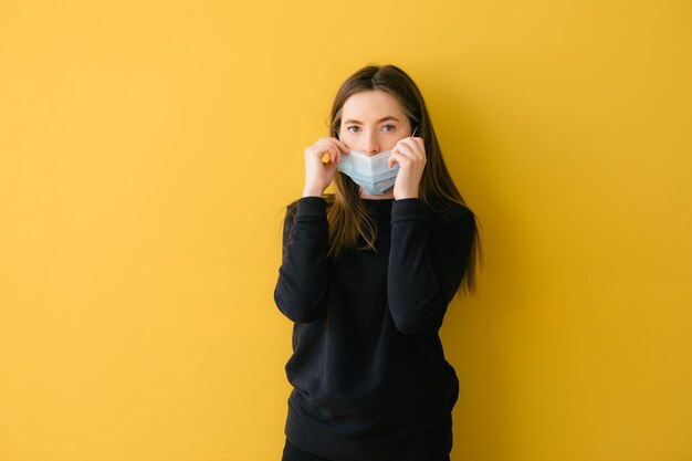 Coronavirus vrouw op gele achtergrond in chirurgisch masker gezichtsbescherming