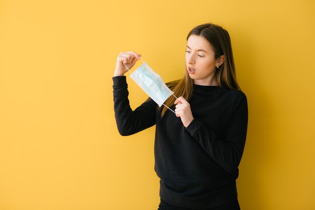coronavirus woman on yellow background in surgical mask face protection