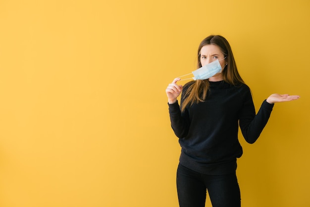 Coronavirus woman on yellow background in surgical mask face protection