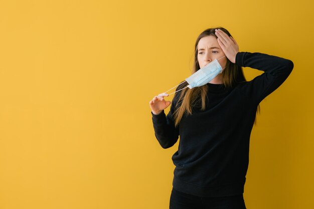 Coronavirus woman on yellow background in surgical mask face protection