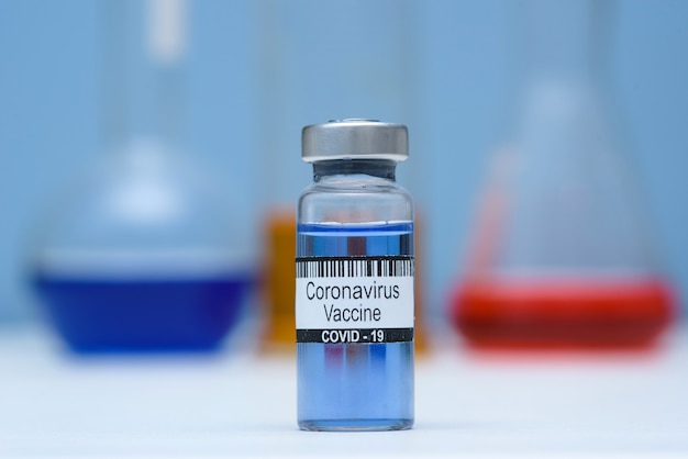 Foto coronavirusvaccin in fles voor injectie op tafel tegen achtergrond medisch laboratorium, ruimte voor tekst. sars-cov-2 coronavirus-epidemie verslaan.