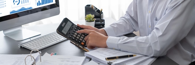 Фото Корпоративный аудитор рассчитывает бюджет с помощью калькулятора на своем офисном столе