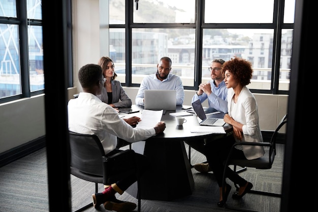 Corporate business colleagues talking in a meeting room seen from doorway