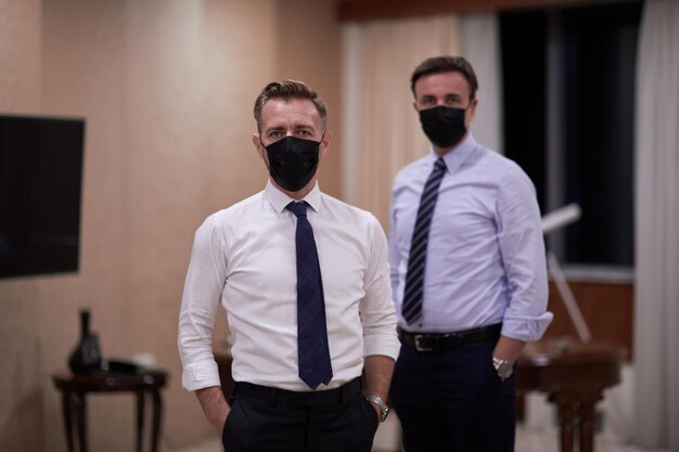 Команда корпоративного бизнеса в маске для защиты от вируса кроны держит социальную дистанцию в роскошном офисе