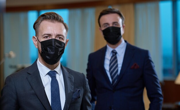 크로나 바이러스 보호 안면 마스크를 쓴 기업 비즈니스 팀은 고급 사무실에서 사회적 거리를 유지합니다