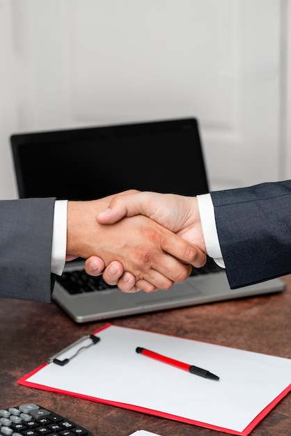 Corporate businessmen handshake indoors.two people\
professionally well dressed gesturing togetherness.working\
colleague partners sign deal in agreement to contract