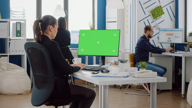 비즈니스 프로젝트를 위해 수평 녹색 화면이 있는 컴퓨터를 사용하는 회사 직원. 키보드를 사용하는 동안 크로마 키와 격리된 모형 템플릿이 있는 모니터를 보고 있는 사업가