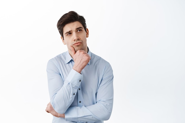 Photo corporate man office manage thinking looking aside and making choice standing thoughtful against white background