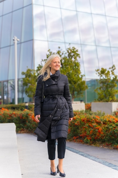 Corporate portrait of middleaged businesswoman walking next to skyscraper exterior