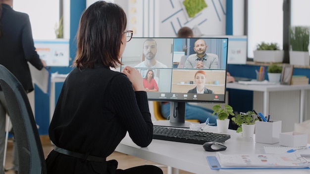 Photo corporate worker talking to colleagues on video call for business project. woman using online conference on computer for marketing strategy and planning with team of corporate workmates