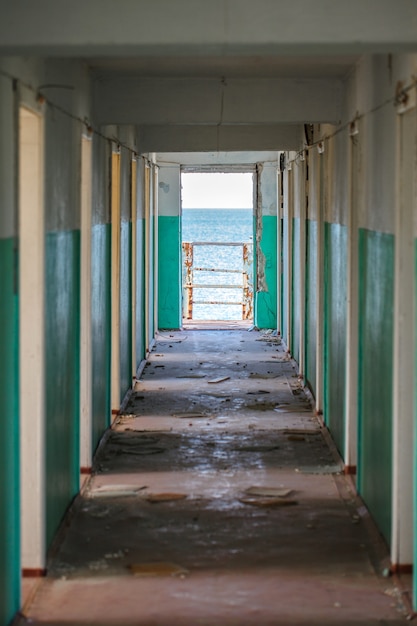 Corridor with doors in an abandoned building during the day and sea view.