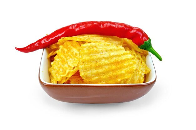 Corrugated potato chips in a clay bowl with fresh red chili peppers isolated