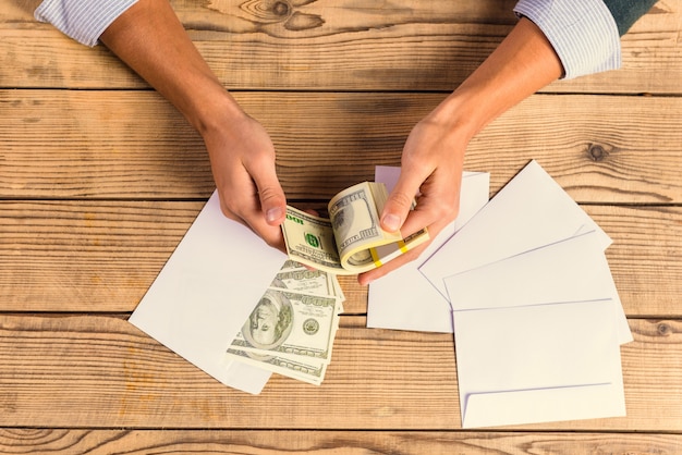 Cose-up businessman counting money on a wooden table.