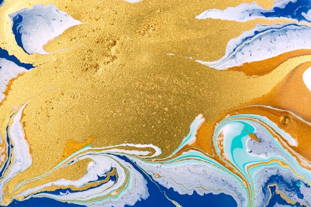 Cose up gold glitter wave on liquid blue and white paint background