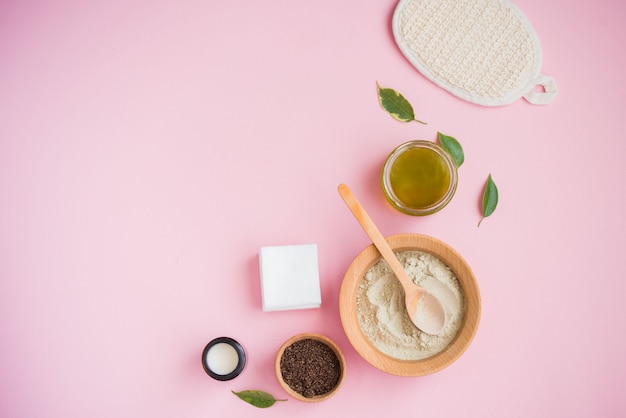 Cosmetic bath salt, grape gomaj for the face, coffee scrub for the body on a pink background.