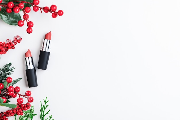 Фото Косметический бьюти-продукт для профессионального праздничного макияжа на рождество. красные помады в виде подарка с рождественским декором, вид сверху. зимняя распродажа косметики. копирование пространства, плоская планировка.