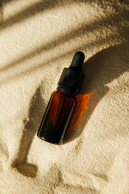 Cosmetic bottle with a pipette on the sand. against the background of sand.