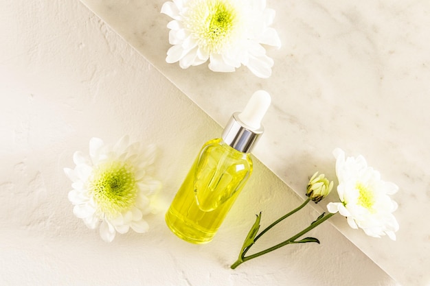Cosmetic bottle with pipette with moisturizing serum lifting effect antiaging agent against the background of a marble slab and white flowers