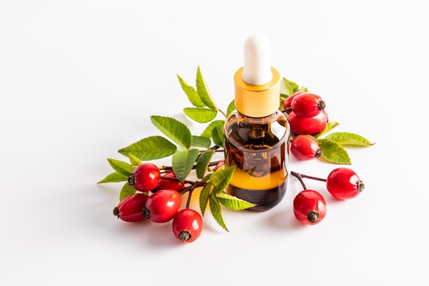 Cosmetic bottle with a pipette with organic rosehip seed oil among ripe fruits on a white background natural cosmetics for skin care A blank layout