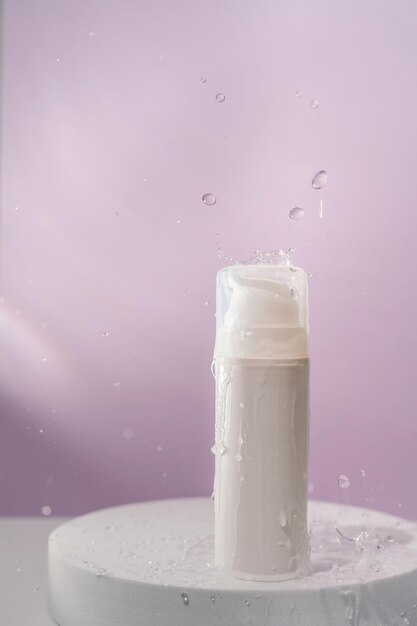 Cosmetic bottle with water splashes on a purple background