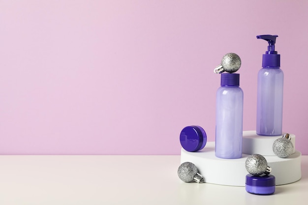 Cosmetic bottles and balls on purple background space for text