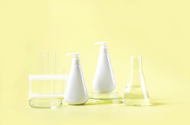 Photo cosmetic bottles and laboratory flasks on a yellow background