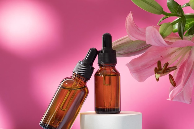 Cosmetic bottles on podium with lily flower and shadow on pink background Face and body care spa concept Hyaluronic acid oil serum with collagen and peptides skin care product