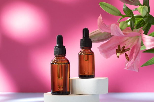 Cosmetic bottles on podium with lily flower and shadow on pink background Face and body care spa concept Hyaluronic acid oil serum with collagen and peptides skin care product