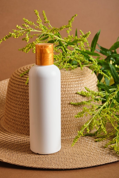 Cosmetic bottles and straw hat on brown background