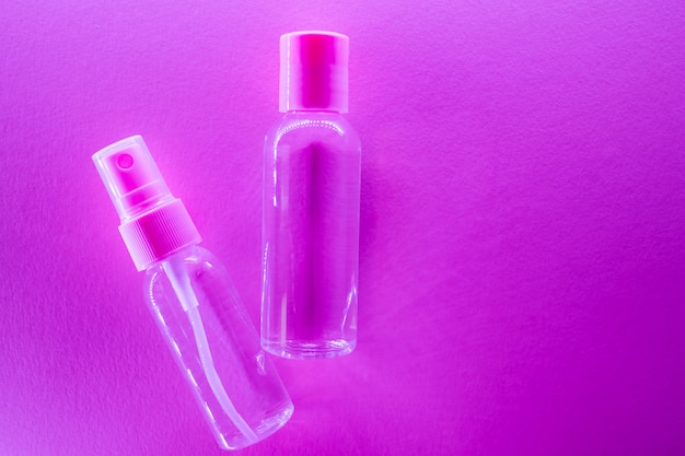 Cosmetic bottles with clear lotion in trendy bright neon light.