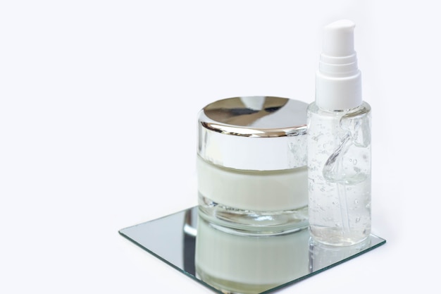 Photo cosmetic bottles with serum, gel, face cream on a mirror. skin cosmetics, minimalism