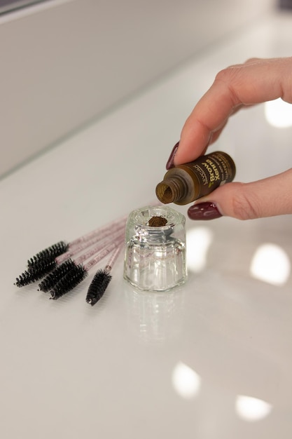 Cosmetic brown henna for eyebrows and eyelashes. In the background are black brushes for eyebrows