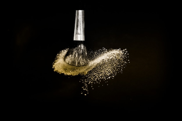 Foto pennello cosmetico con polvere cosmetica dorata spalmabile
