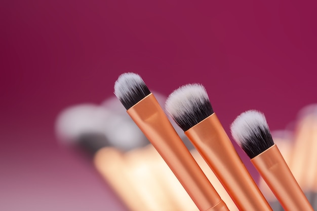 Cosmetic brushes of different sizes on pink